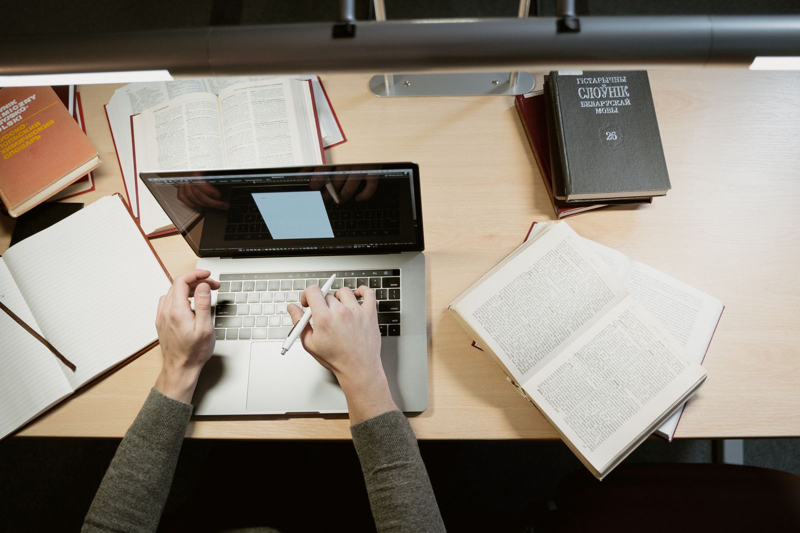 Student radi za laptopom uz knjige i beleške na radnom stolu